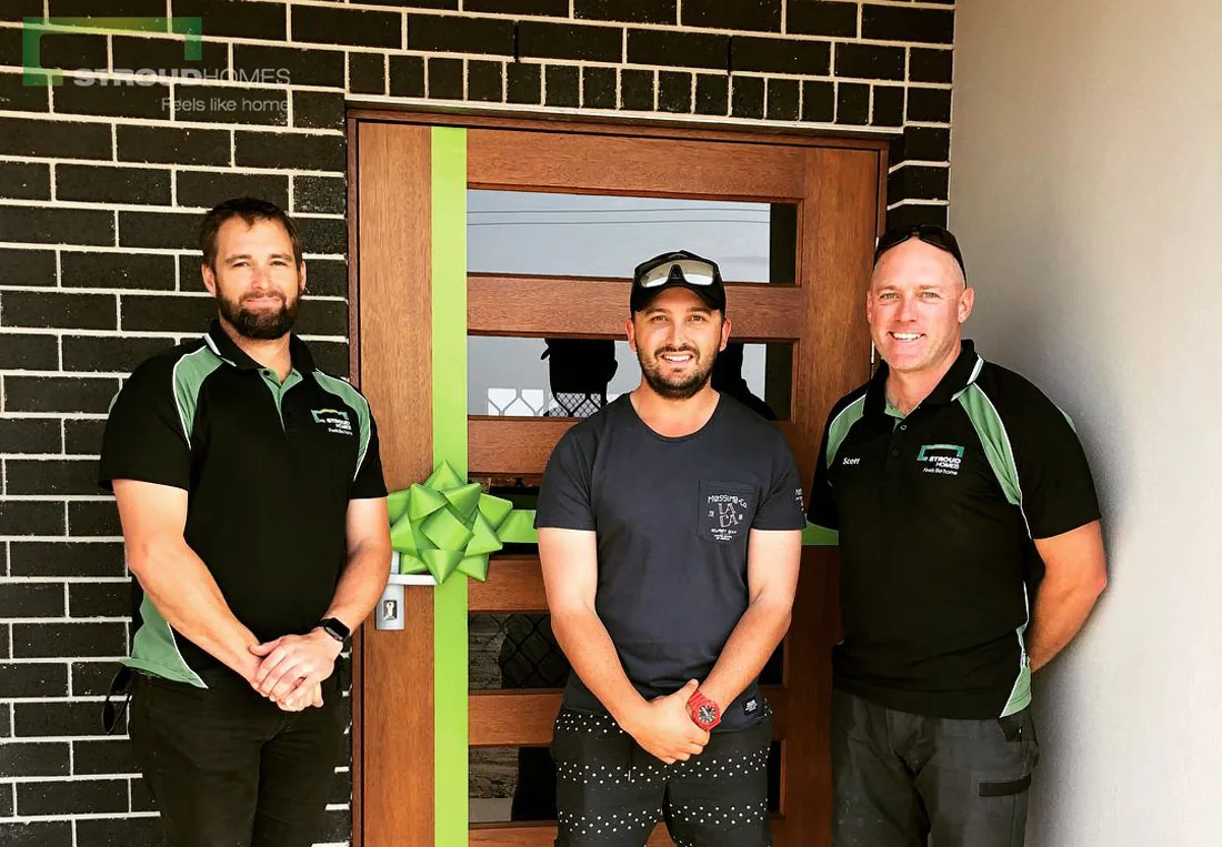 A Stroud Homes team handing over the keys to a new home at the front door